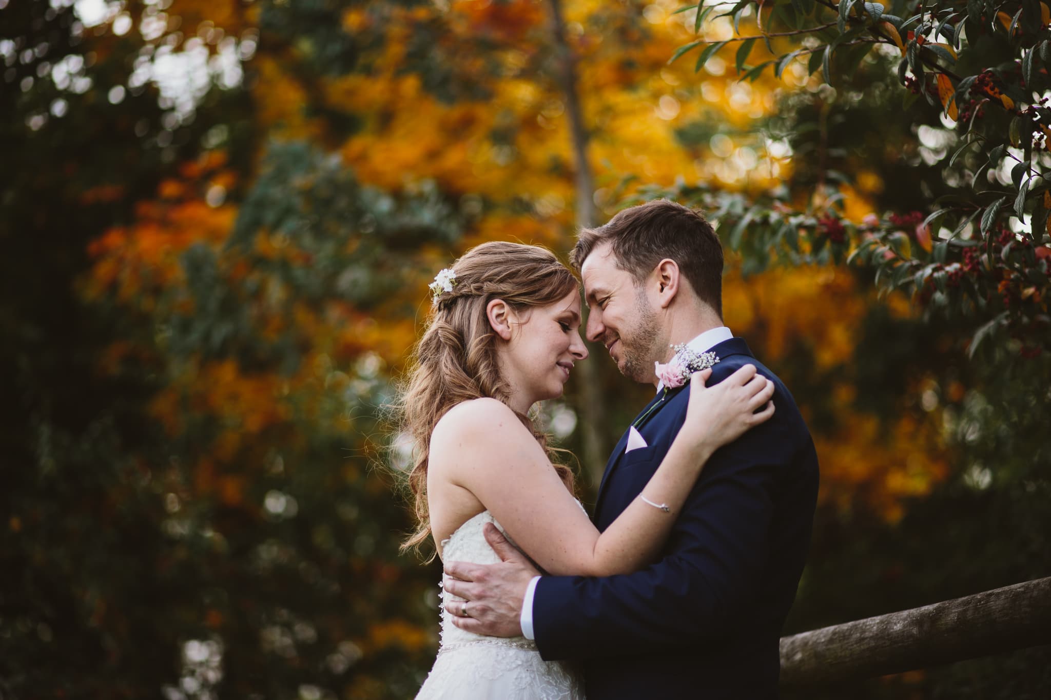 Wedding photography at Mythe Barn - couple portraits against autumn leaves. Bride and groom heads touching looking at each other.