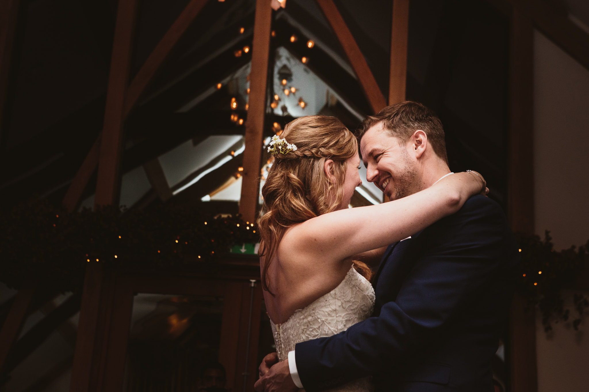 Wedding photography at Mythe Barn - close up of couple during first dance, lights reflected in window of the barn