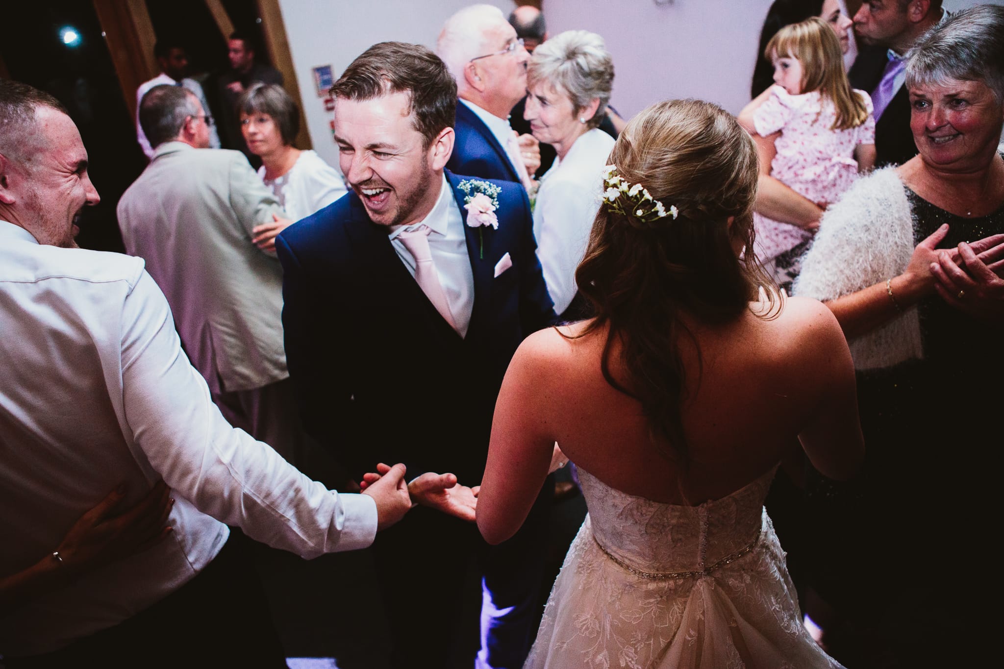 Wedding photography at Mythe Barn, couple on dance floor surrounded by guests. Groom laughing