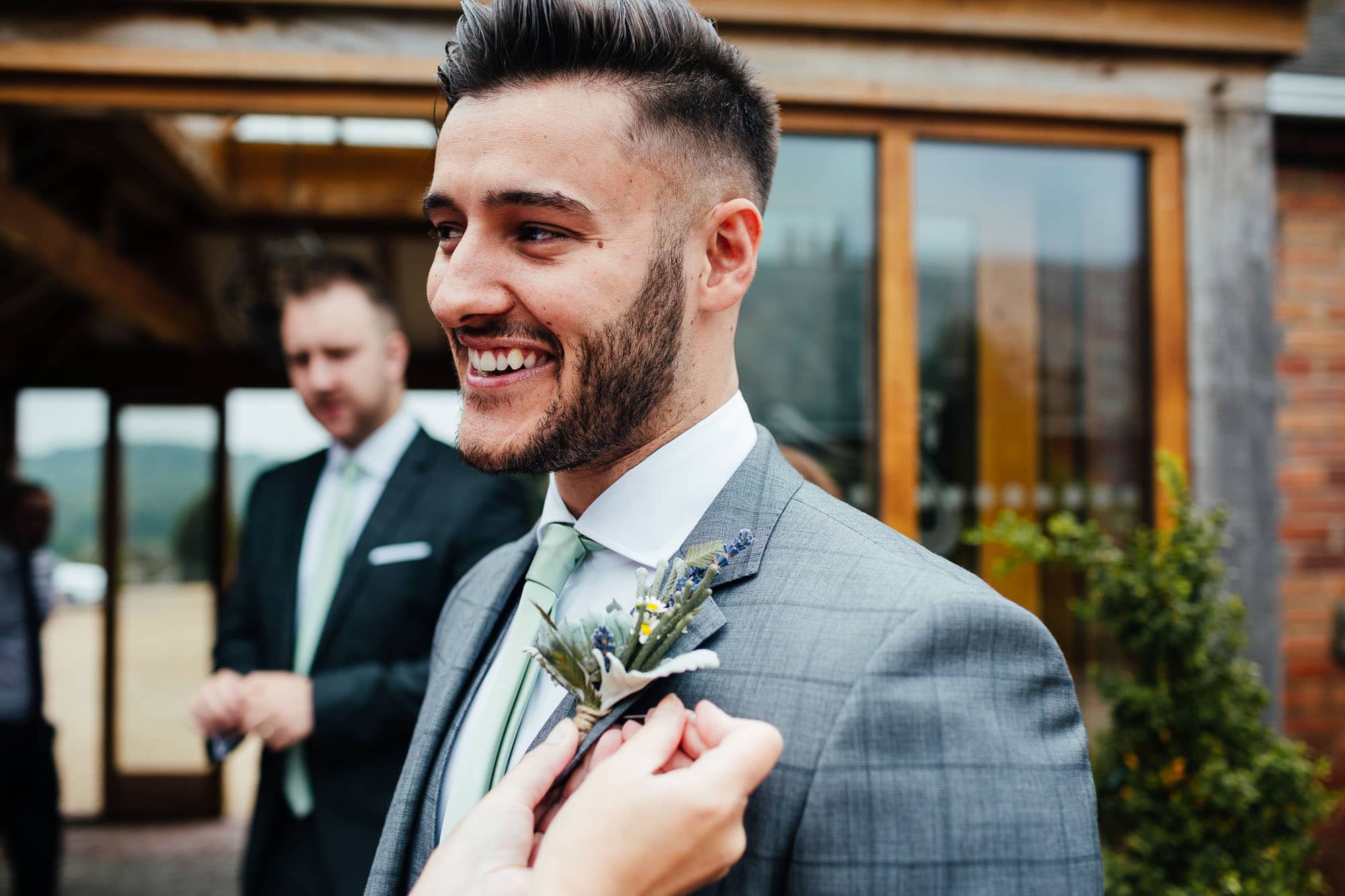 Wedding photography at Swancar Farm - groom having button hole pinned in