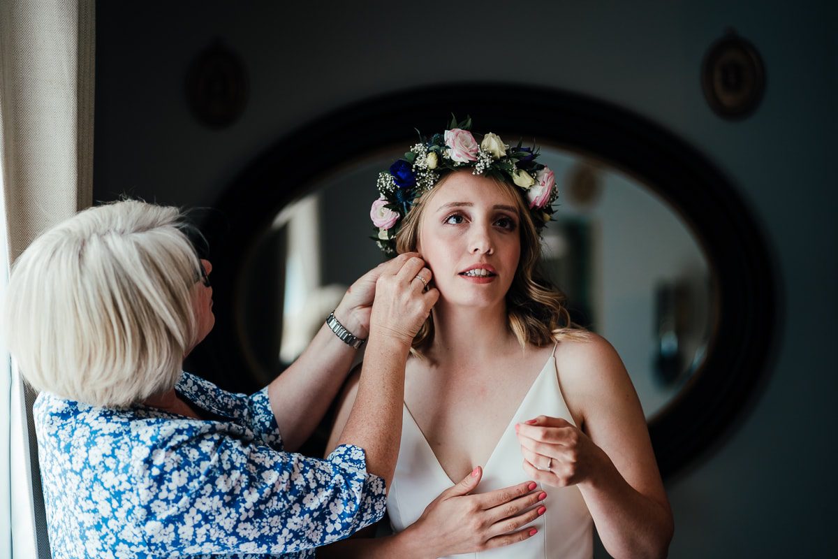 Mother putting bride's earrings in