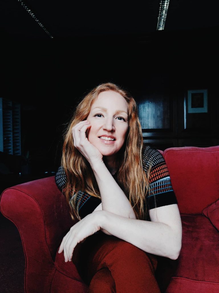 virtual photoshoot - Chrissie sitting forward in red armchair looking to camera