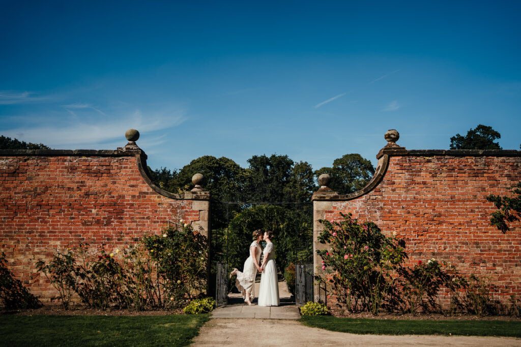 Wedding photography at Thorpe Garden: Brides having a kiss at the gates to walled garden.