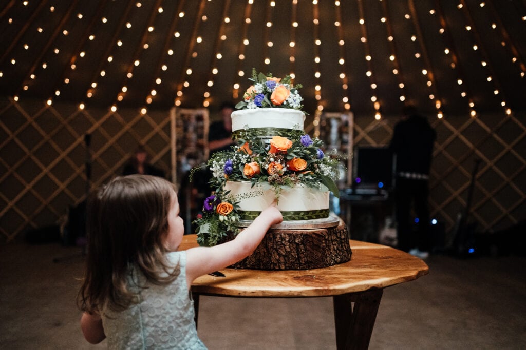 Small girl touching wedding cake,.
