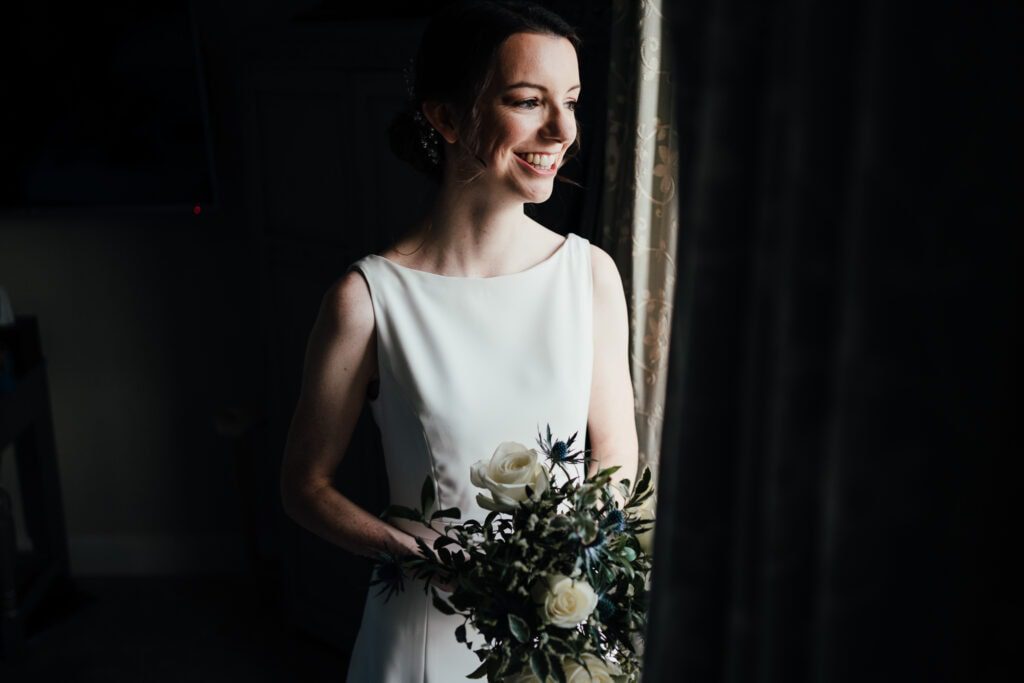 Wedding photography at Widbrook Grange: Bride looking out of window in beautifully lit bridal portrait