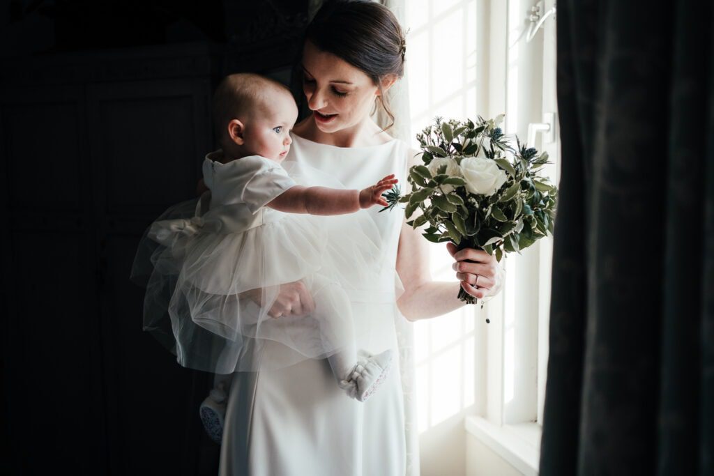 Wedding photography at Widbrook Grange: baby reaches for bride's flowers