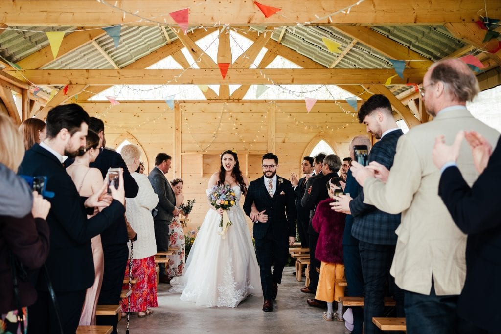Bride and groom walk back down the aisle at the Hidden Hive