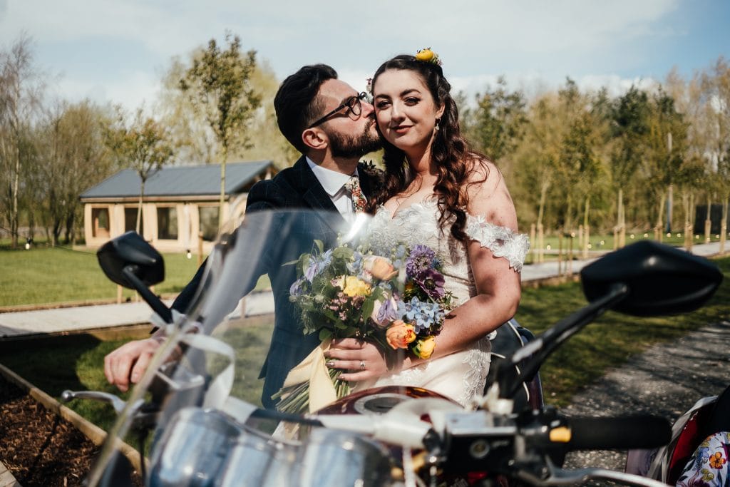 Bride and groom share kiss on motorbike