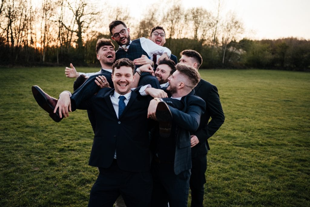 Fun photo at the Hidden Hives wedding venue outside the tipis. Groom being carried by groomsmen