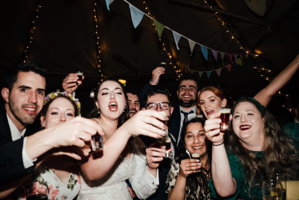 bride and groom with their friends all about to take a shot at the bar