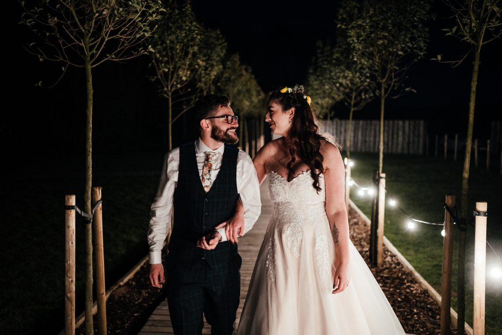 Bride and groom walking down the pathway lit up in the dark