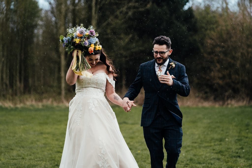Bride and groom running from the rain at the Hidden Hive wedding venue in Nottinghamshire