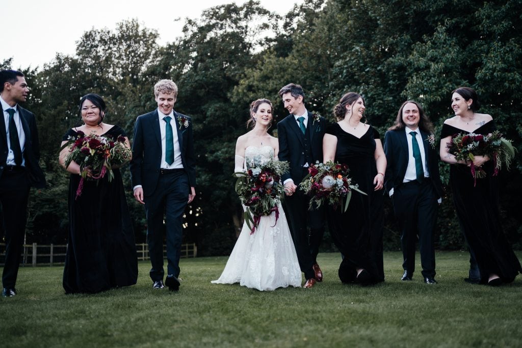 Bride and groom with bridal party walking across the grass