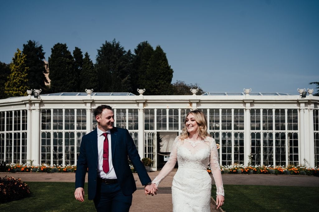 Bride and groom walking towards camera outside orangery