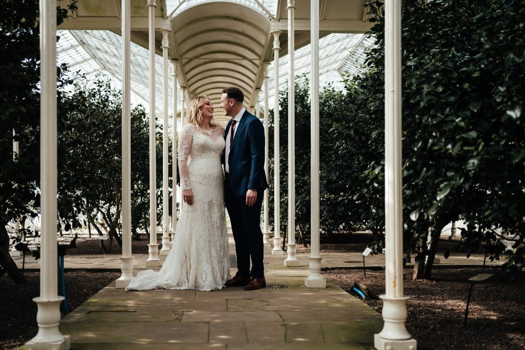 Bride and groom laughing standing in Camellia House