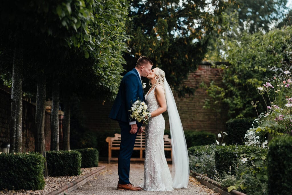 Bride and groom portrait sharing a kiss at The Walled Garden at Beeston Fields
