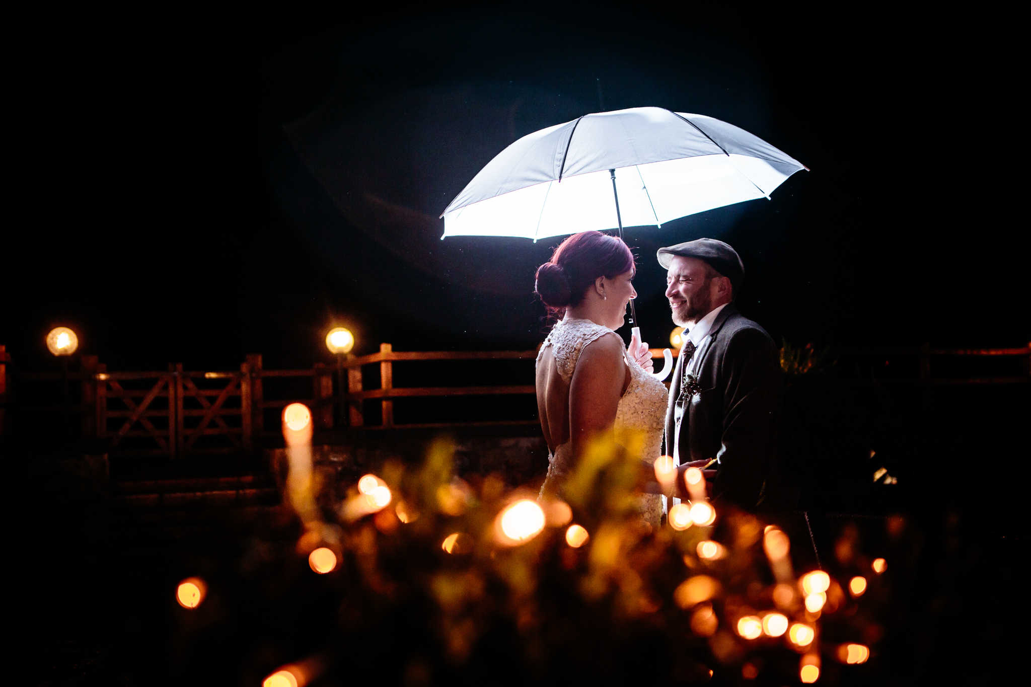 bride and groom at night under a brolly groom laughing 