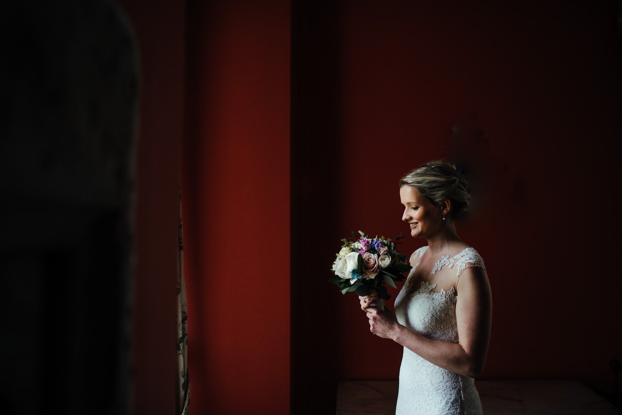 Bride standing in the bridal suite looking at her bouquet.