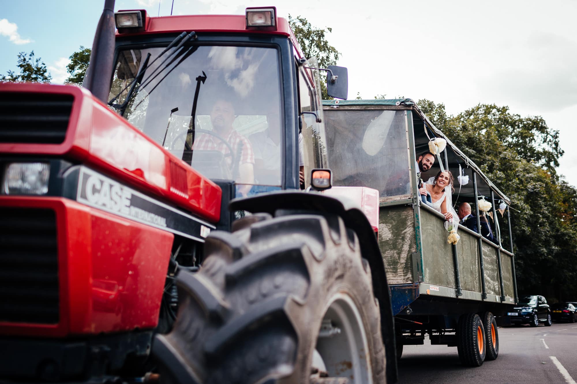 Bridge House Barn Wedding - Bride and groom wave from the tractor as they are driven off to the venue.