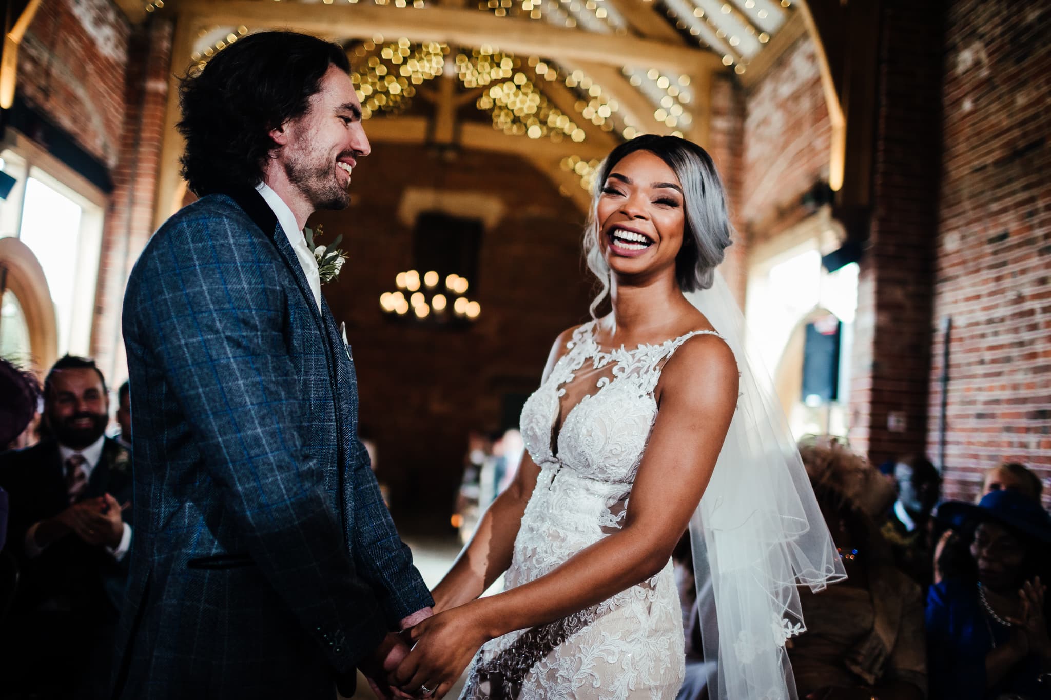 Barn weddings in Nottingham: Hazel gap barn wedding ceremony. Bride laughing, groom looking at bride.