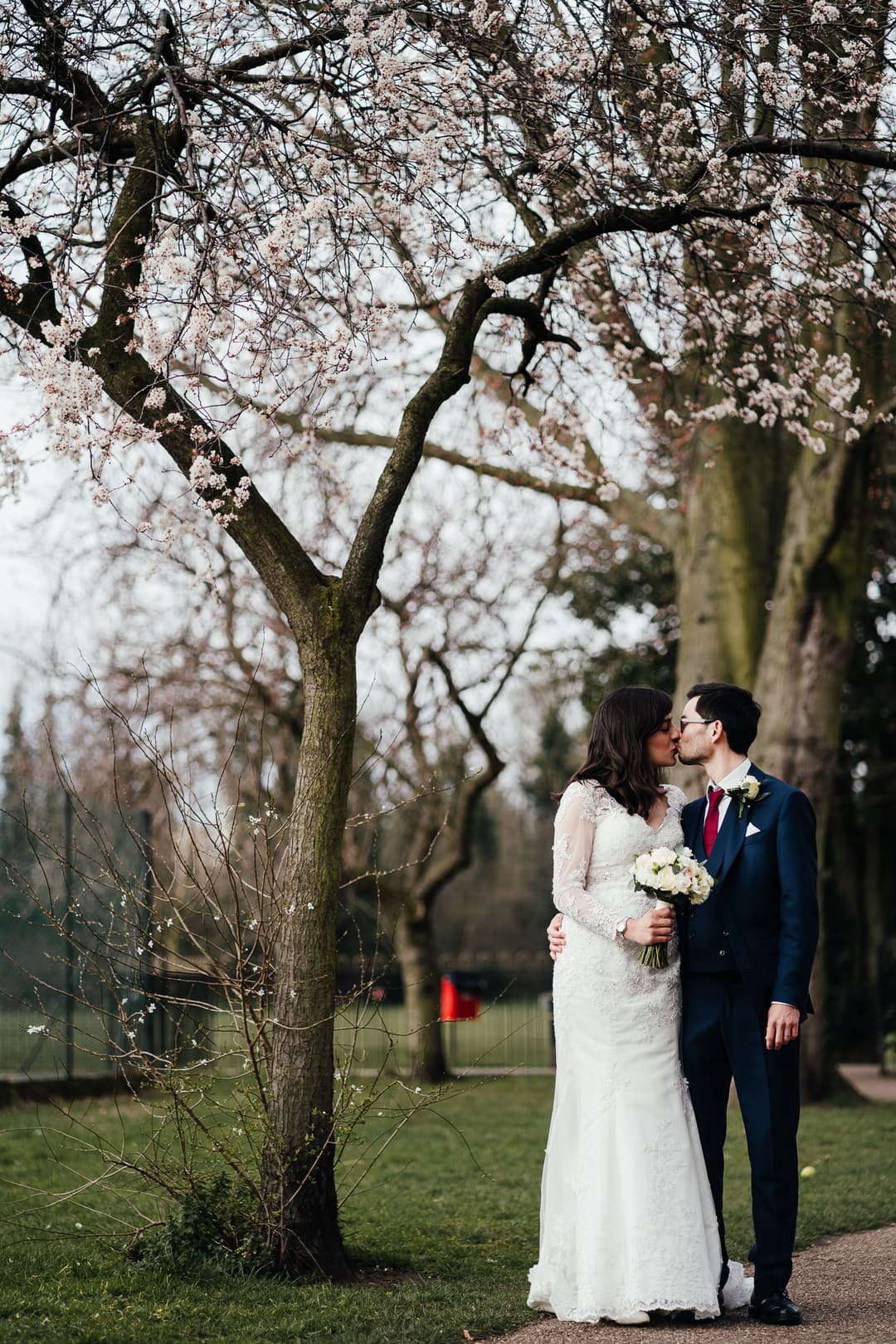 Wedding at West Bridgford Registry Office: Bride and groom kiss under a Spring blossom tree