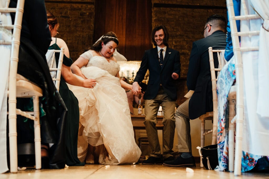 bride and groom jump over broom in rustic pagan wedding
