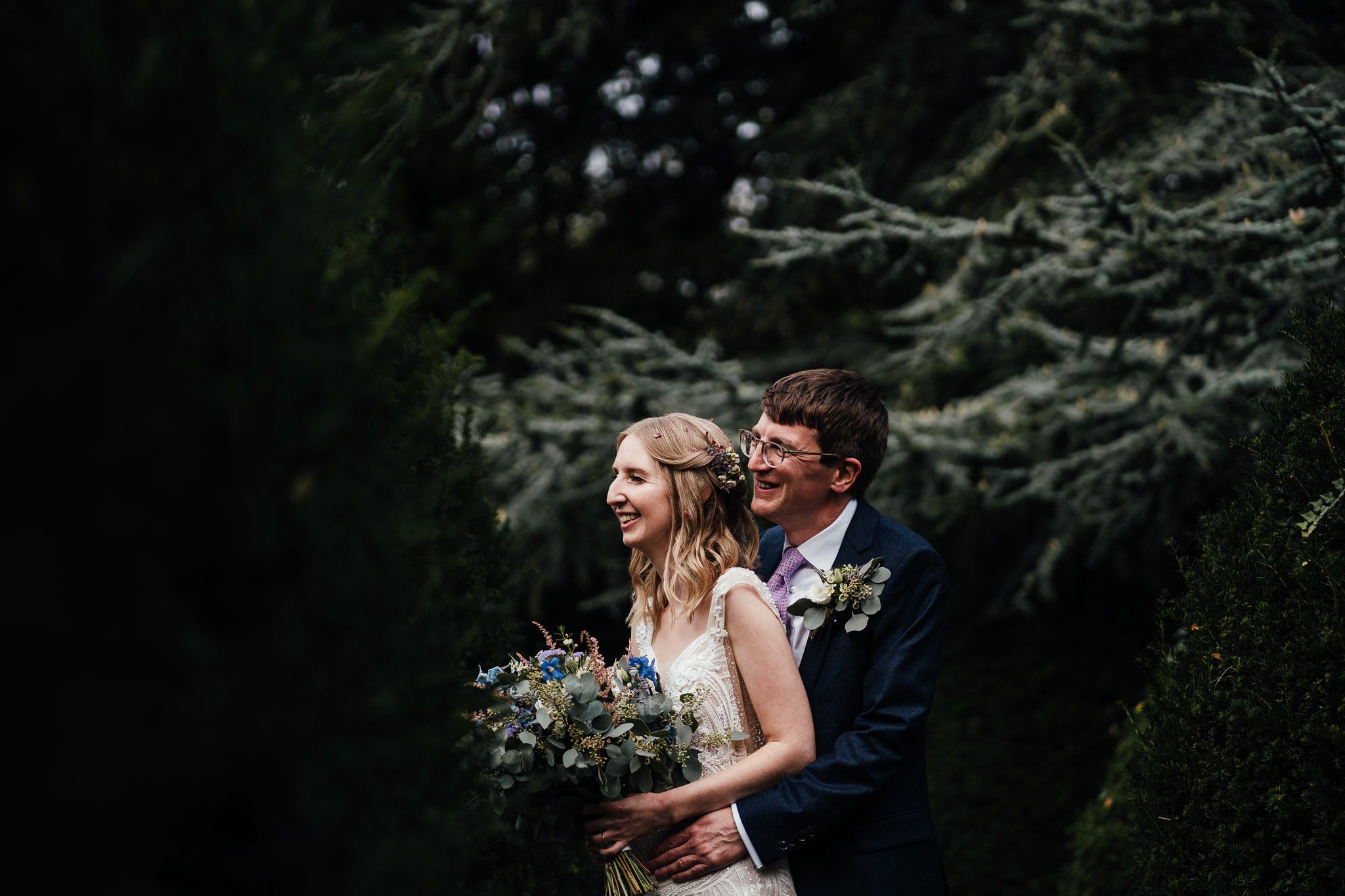 Bride and groom portrait in a pool of light in the grounds of the church