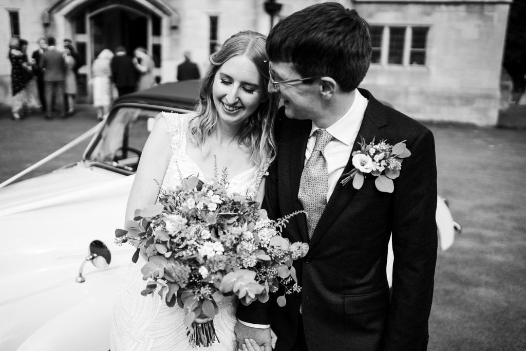 Bride and groom in a natural pose by their little vintage Morris Minor