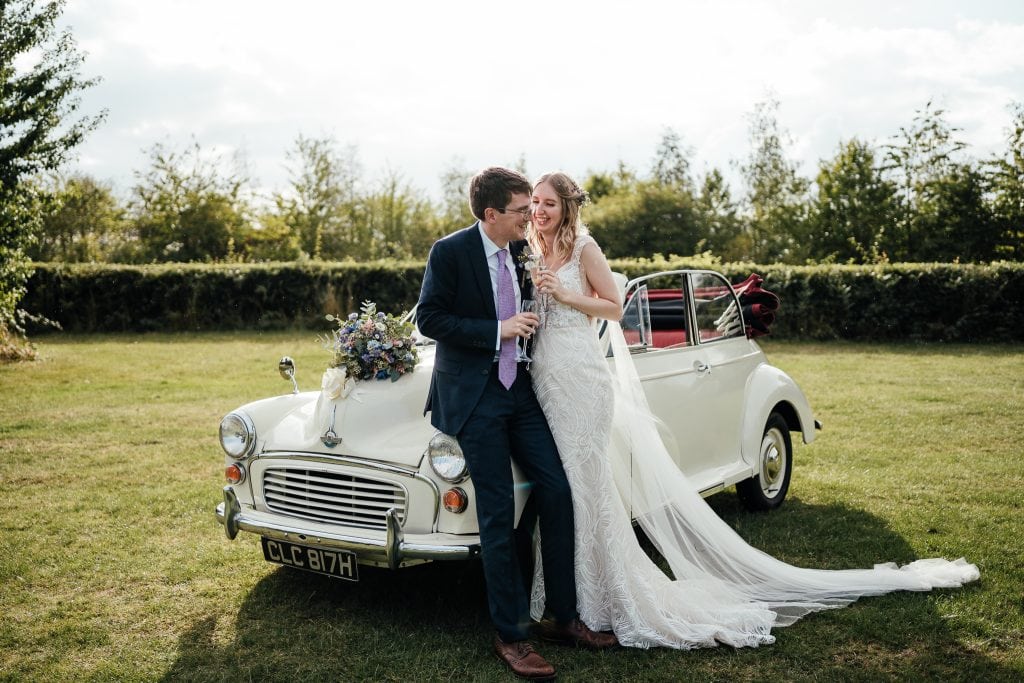 Wedding at The Manor House Quorn: Bride and groom standing outside of their Morris Minor