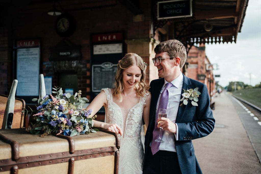 Wedding at The Manor House Quorn: Bride and groom leaning on luggage at the steam railway platform