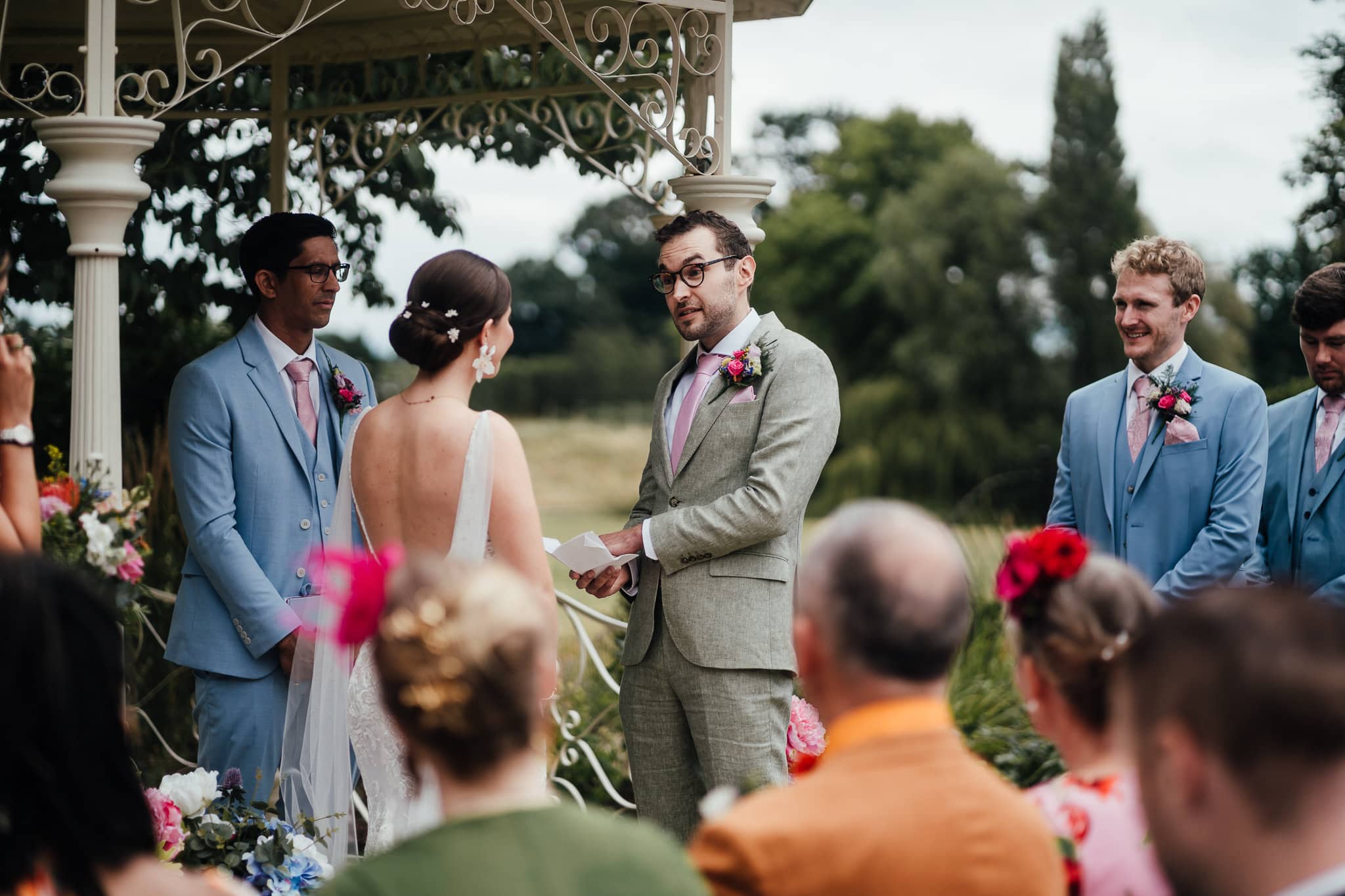 Outdoor wedding ceremony at Norwood Park. Groom reads vows to bride