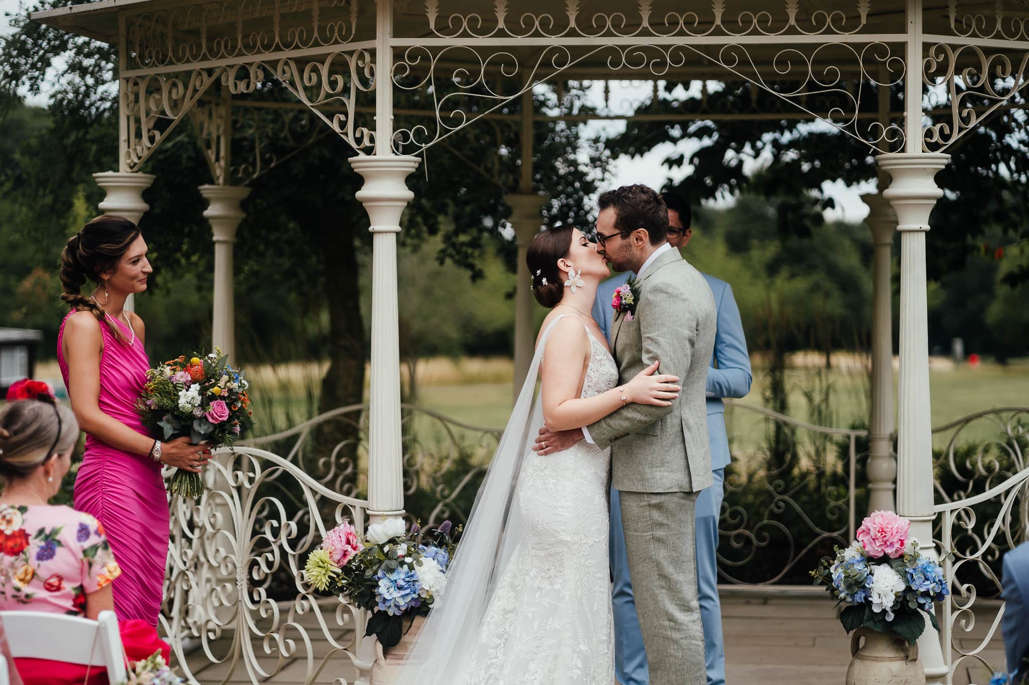 Bride and groom kiss under gazebo in outdoor ceremony at Norwood Park