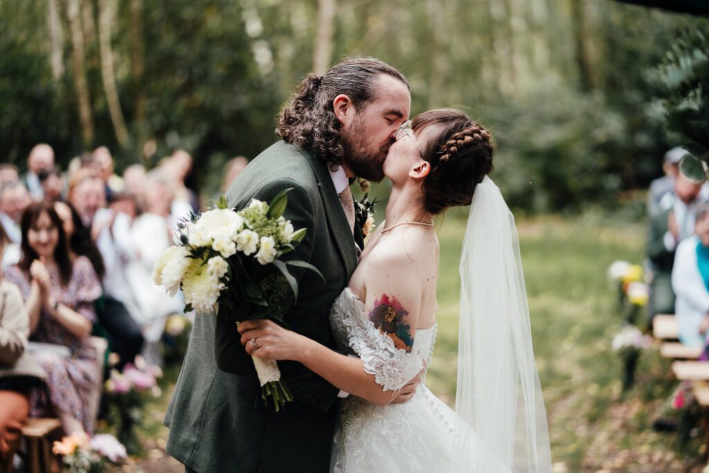Bride and groom kiss at the end of the ceremony. Outside in woodland at Sherwood Glade