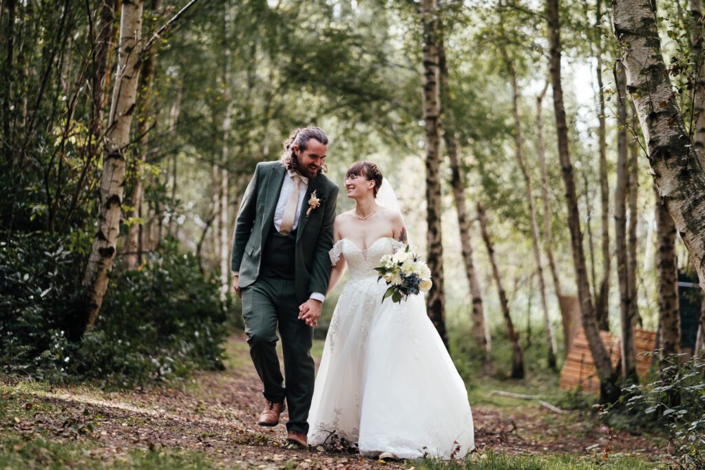 Bride and groom walking through woodland at Sherwood Glade