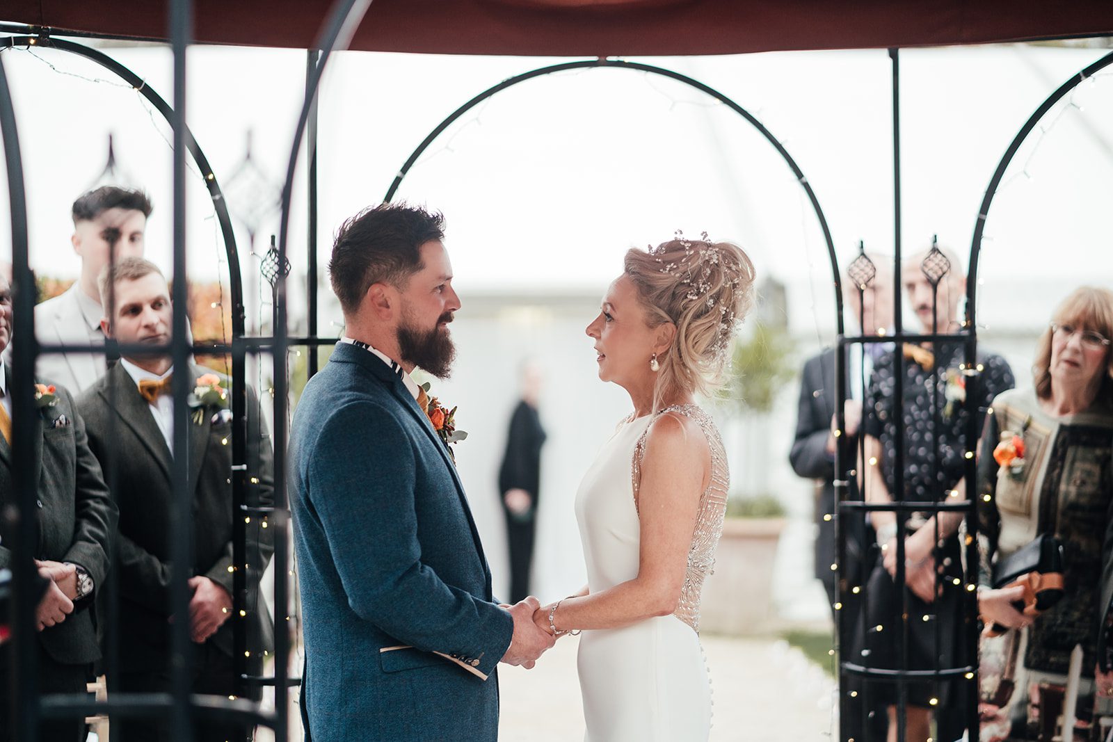 Wedding photography at Pippley Walled Garden. Bride and groom in their outdoor ceremony under the pergola holding hands.