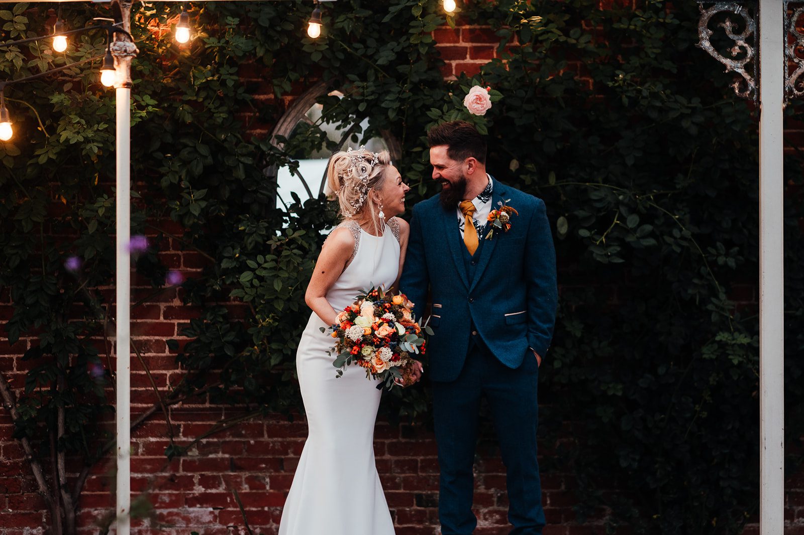 Wedding Photography at Pippley Walled Garden. Bride and groom in a relaxed full length portrait, turned towards each other laughing