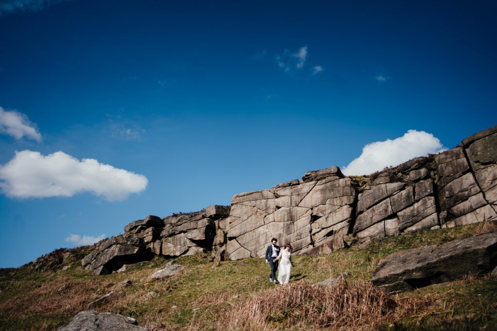 bride and groom walk down from rocky peaks