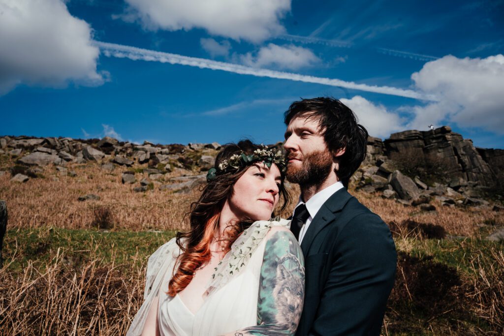 Bride and groom heads close together looking out. Blue skies