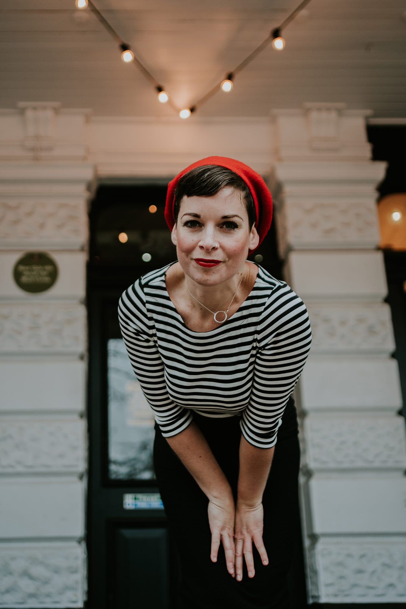Nottingham wedding photographer Kathryn Edwards wearing a stripy top and a red beret, leaning in towards the camera, with a friendly smile