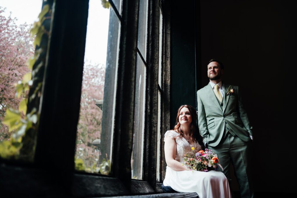 Bride and groom on staircase by window at Hargate Hall