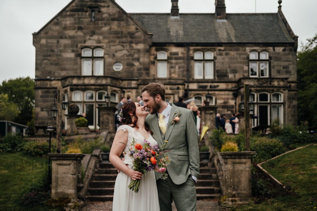 Bride and groom about to kiss on steps of Hargate Hall.